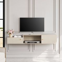 a flat screen tv sitting on top of a white entertainment center next to a window