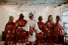 a group of women in red robes standing next to each other near a window with string lights