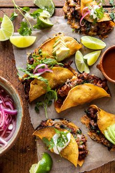 some tacos are sitting on a piece of paper next to a bowl of sauce