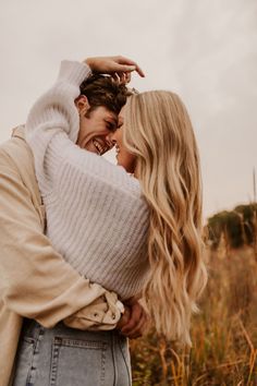 a man and woman hugging in the middle of a field