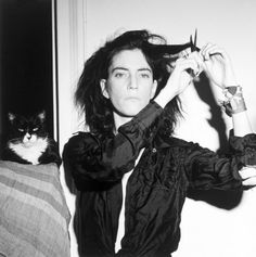 a black and white photo of a woman cutting her hair with a pair of scissors