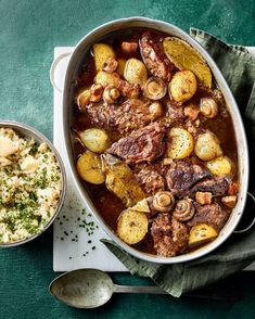 a large pot filled with meat and potatoes next to a bowl of mashed potatoes