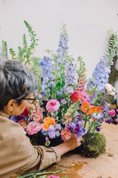 an older woman arranging flowers on a table