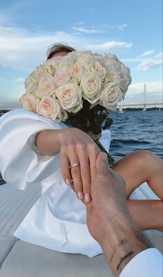 a man and woman holding hands while sitting on the back of a boat with flowers in their hair