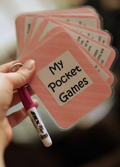 a person holding a pen and some cards with words on them that say my pocket games