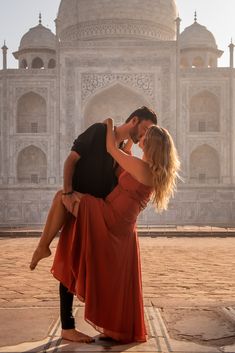 a man and woman kissing in front of a building