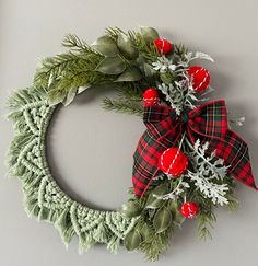 a christmas wreath hanging on the wall with red berries and greenery attached to it