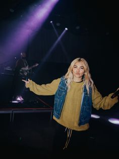 a woman standing in front of a stage with her arms spread out to the side