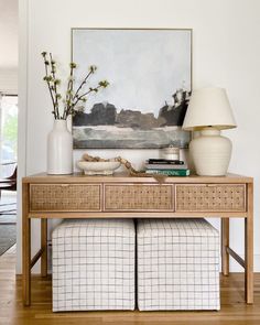 a table with two vases on top of it and a lamp next to it