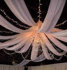 the ceiling is decorated with white drapes and lights