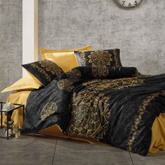 a black and yellow comforter set on a bed with a clock in the background