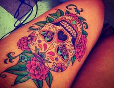 a woman's thigh with a colorful sugar skull tattoo on it