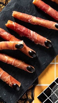 several pieces of meat wrapped in bacon on top of a cutting board next to a knife