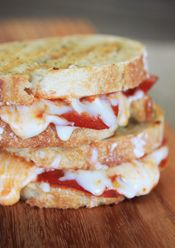 two sandwiches with meat, cheese and vegetables are on a piece of paper next to a fork