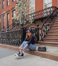 a woman sitting on the ground in front of some stairs with her shoes and bag