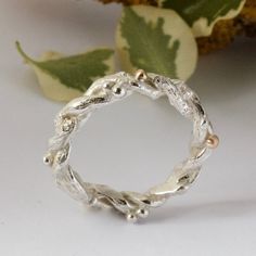 a silver ring sitting on top of a table next to a leafy green plant