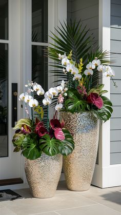 two large potted plants sitting on the side of a house