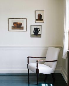 a white chair sitting next to a wall with pictures on it