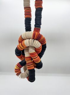 an ornament made out of strips of yarn hanging from a hook on a white background