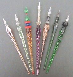 seven different colored toothbrushes lined up in a row on a gray surface,