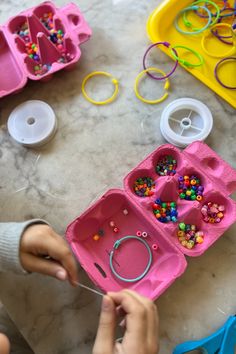 a child is playing with beads and plastic trays