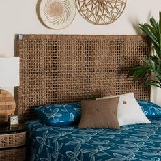 a bed with blue sheets and pillows next to a wall mounted wicker basket on the wall