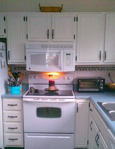 a white stove top oven sitting inside of a kitchen next to a sink and microwave