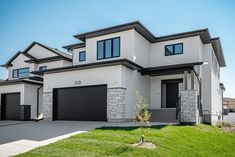 a two story house with garages and grass in front