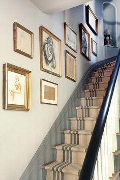 a staircase with pictures on the wall and carpeted stairs leading up to the second floor