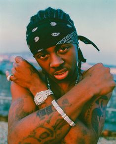 a young man with tattoos on his arms and chest poses for the camera while wearing a beanie