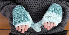 a person wearing crocheted mittens and holding their hands in the middle of them