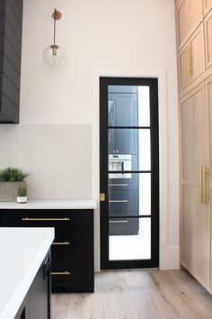 a kitchen with black doors and white counter tops next to a wooden flooring area