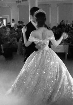 a man and woman dance together in front of an audience at a formal event, dressed in sparkling sequins