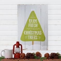 a wooden sign that says farm fresh christmas trees next to pine cones and mugs