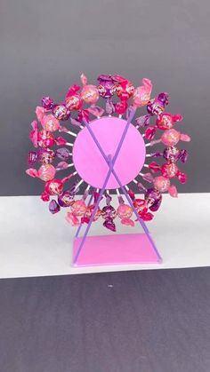 a ferris wheel made out of candy on a pink base and purple stand with white background