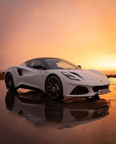 a white sports car parked on the beach at sunset