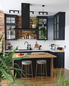 an open kitchen with black cabinets and wooden counter tops, white subway backsplash