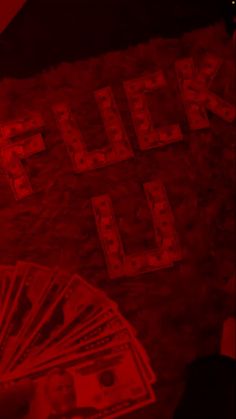 a bunch of money sitting on top of a table next to a red lit sign