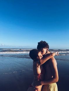 a man and woman hugging on the beach