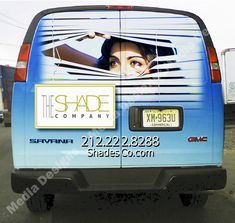 the back end of a blue van with a woman's face painted on it