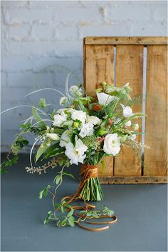 a bouquet of white flowers sitting on top of a table next to a wooden crate