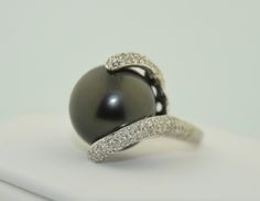 This is an impressively large pearl ring. The pearl is a south Sea Black Tahitian Pearl. The pearl is drilled and mounted with pave diamond accents. The small prong is drilled on the side and the fingers of diamonds are securing the pearl with no movement. This pearl is big, measuring in at 15.5 mm. It is a deep grey/black, perfectly round. There are a couple of natural dimples on the side not the top of the pearl as photographed The setting is 14K White gold, not hallmarked but tested and guara Luxury Tahitian Pearl Jewelry With Brilliant Cut, Fine Jewelry With Tahitian Pearl And Diamond Accents, Formal Black Tahitian Pearl Ring, Tahitian Pearl Jewelry With Brilliant Cut, Tahitian Pearl Jewelry With Diamond Accents For Wedding, Luxury Tahitian Pearl Jewelry With Diamond Accents, Black Tahitian Pearl Ring, Tahitian Pearl Ring With Diamond Accents For Wedding, Tahitian Pearl Ring With Diamond Accents Fine Jewelry