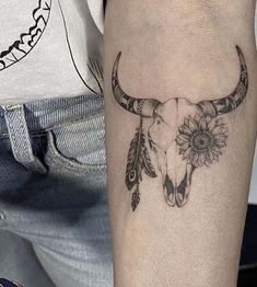 a bull's skull with flowers and feathers on the arm is shown in black ink