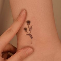 a small tattoo on the ankle of a woman's left foot with a flower