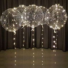 three clear balloons with lights hanging from them