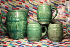 four green mugs sitting next to each other on top of a colorful table cloth