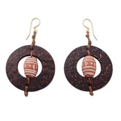 Ornate terracotta beads center coconut shells in the design of these bold earrings. The design of the earrings makes me think of medieval architecture says Nonyem Abena Ibeneme. The earrings are crafted by hand with waxed linen cords and brass hooks. Bohemian Brown Round Earrings, Brown Bohemian Round Earrings, Brown Round Bead Earrings For The Beach, Earthy Brown Earrings For Festivals, Artisan Brown Beaded Earrings For Pierced Ears, Handmade Bohemian Brown Plug Earrings, Handmade Brown Bohemian Plug Earrings, Adjustable Traditional Earrings For Beach, Traditional Brown Drop Earrings Jewelry