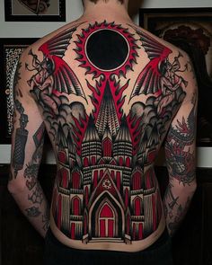 the back of a man's body with an intricate tattoo design on his chest