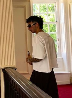 a man standing on top of a stair case next to a window holding a beer