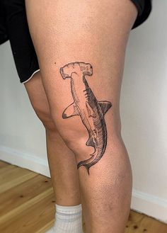 a man with a shark tattoo on his leg, standing in front of a wall